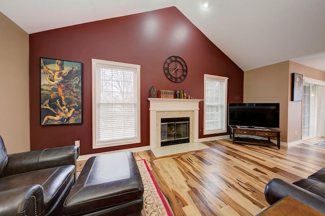 living room with hardwood / wood-style floors, a high end fireplace, and vaulted ceiling