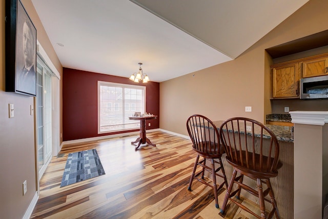 dining area featuring light hardwood / wood-style floors, an inviting chandelier, and lofted ceiling