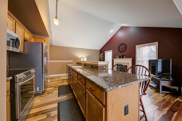 kitchen with sink, stainless steel appliances, pendant lighting, a breakfast bar, and a center island with sink