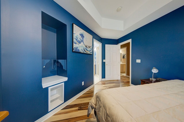 bedroom featuring hardwood / wood-style floors and a raised ceiling