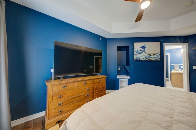 bedroom with connected bathroom, a raised ceiling, and ceiling fan