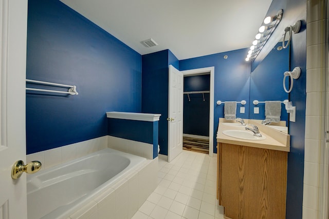 bathroom with tile patterned floors, vanity, and tiled bath