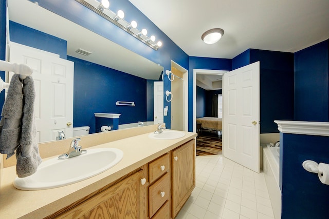 bathroom featuring tile patterned flooring, vanity, toilet, and a tub