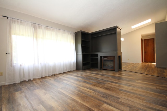 unfurnished living room featuring a wealth of natural light, dark wood-type flooring, and vaulted ceiling