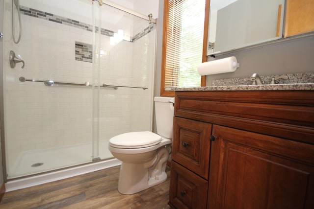 bathroom featuring hardwood / wood-style floors, vanity, toilet, and a shower with shower door