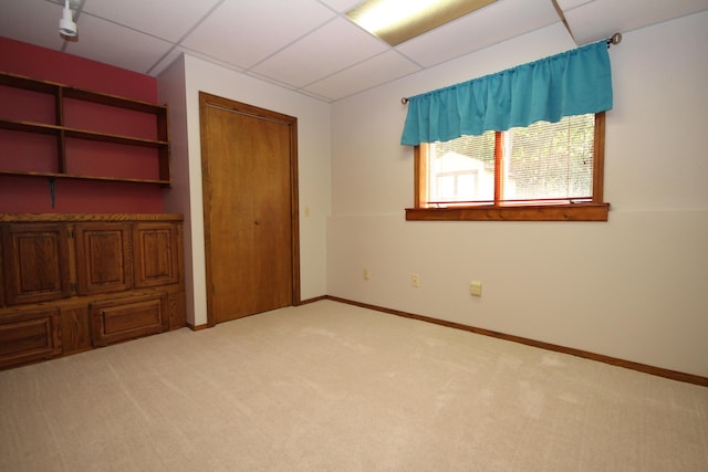 unfurnished bedroom with light carpet and a drop ceiling