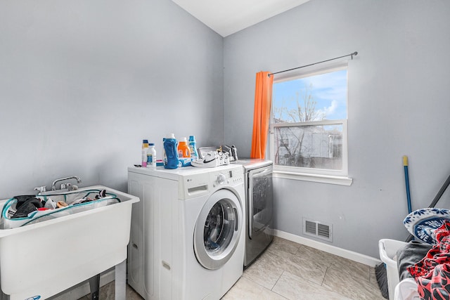 laundry room with light tile patterned floors, washer and clothes dryer, and sink