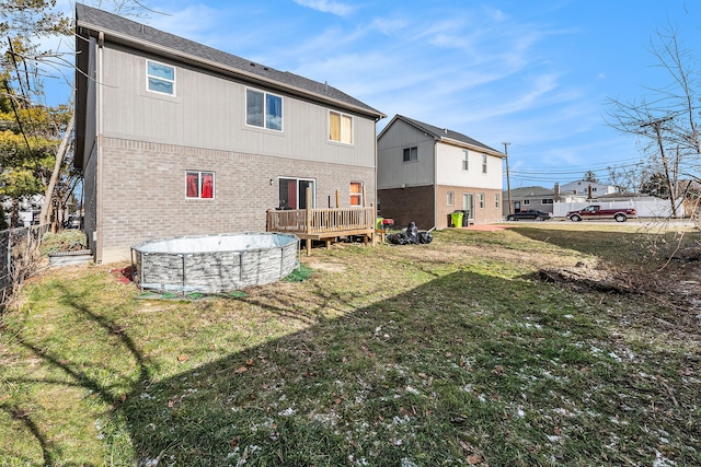 rear view of house featuring a pool side deck and a yard