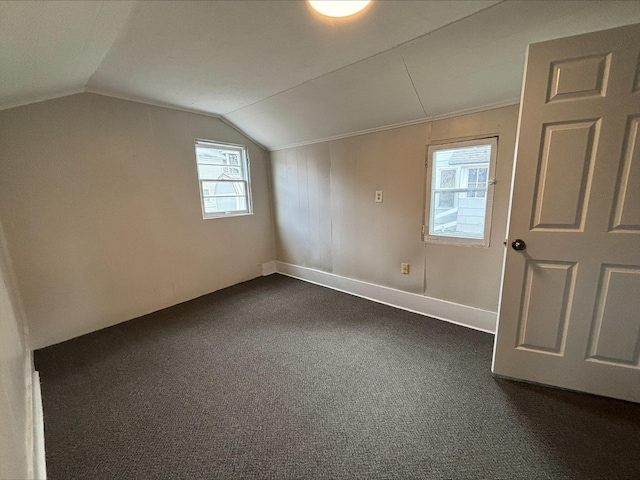 additional living space featuring dark carpet and vaulted ceiling