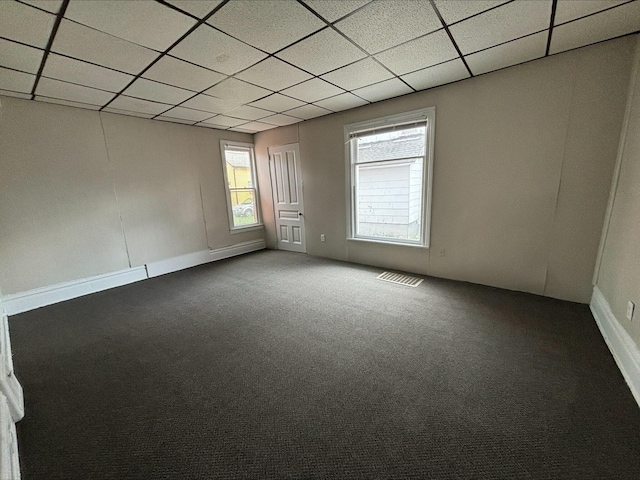 carpeted empty room featuring a drop ceiling