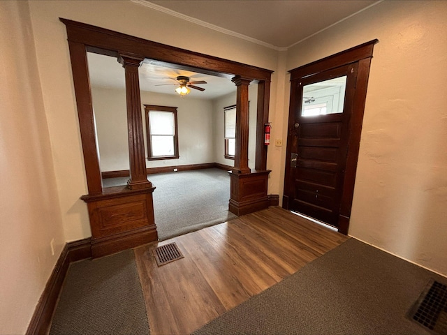 foyer entrance featuring ornate columns, ceiling fan, crown molding, and wood-type flooring