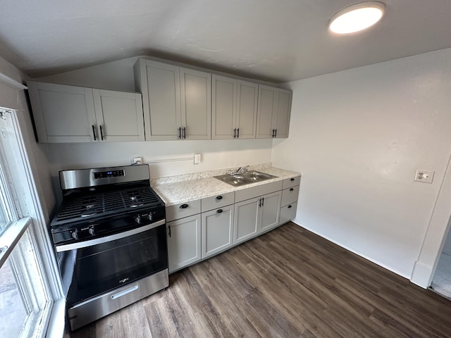 kitchen with gray cabinetry, stainless steel gas range oven, lofted ceiling, and sink