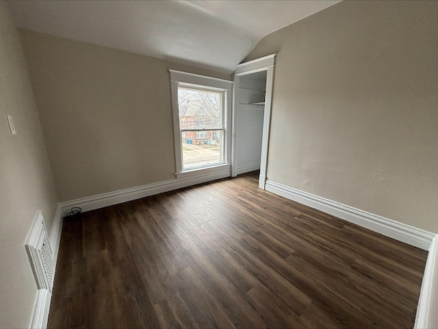 spare room with dark wood-type flooring and vaulted ceiling