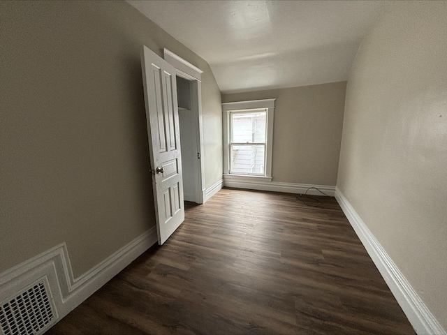 spare room with lofted ceiling and dark wood-type flooring