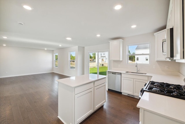 kitchen with sink, appliances with stainless steel finishes, dark hardwood / wood-style flooring, a kitchen island, and white cabinets