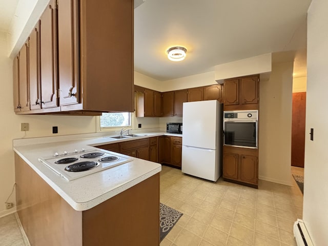 kitchen featuring sink, kitchen peninsula, white appliances, and baseboard heating