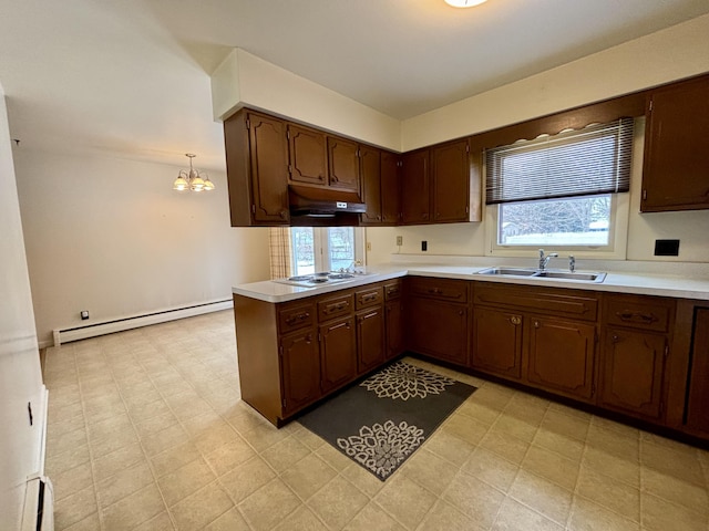 kitchen with white cooktop, sink, kitchen peninsula, pendant lighting, and a baseboard heating unit