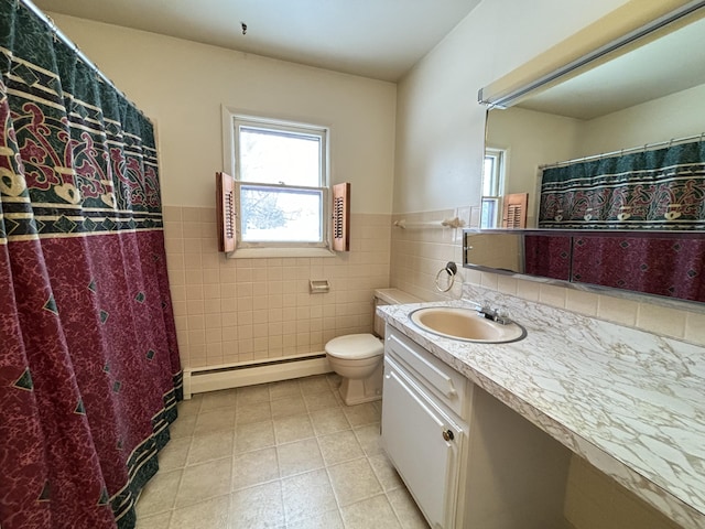 bathroom with tile walls, tile patterned flooring, vanity, a baseboard heating unit, and toilet