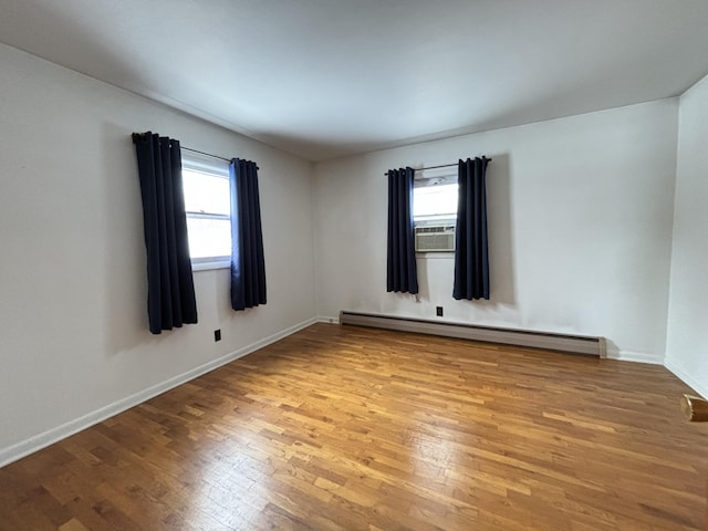 unfurnished room featuring a baseboard radiator, a healthy amount of sunlight, cooling unit, and light hardwood / wood-style floors