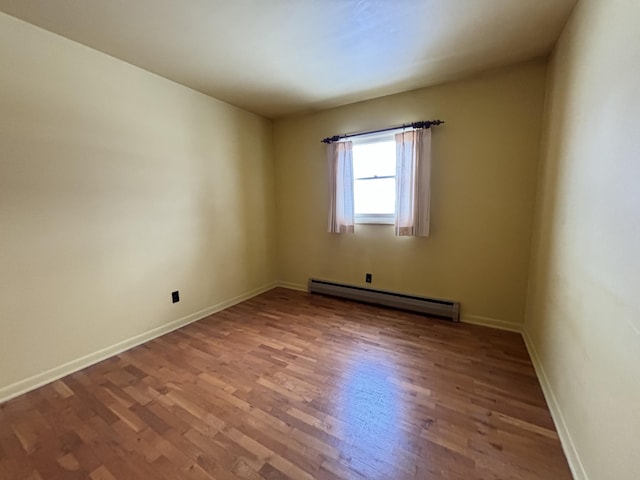 empty room with light hardwood / wood-style flooring and a baseboard heating unit