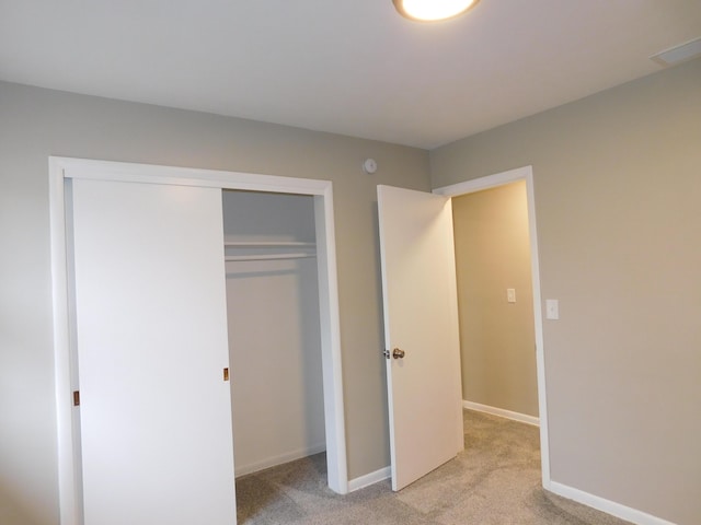 unfurnished bedroom featuring light carpet and a closet