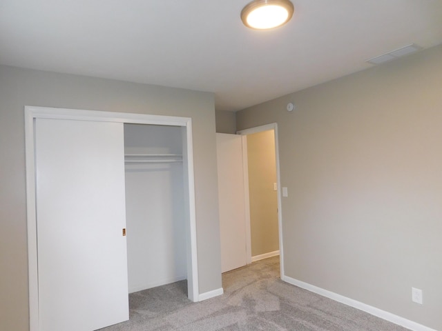 unfurnished bedroom with light carpet and a closet