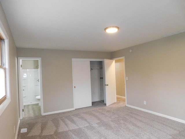 unfurnished bedroom featuring connected bathroom, light colored carpet, and a closet