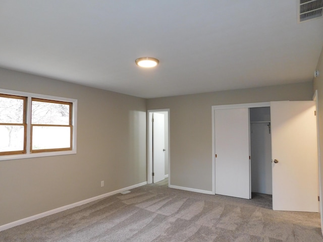 unfurnished bedroom featuring light colored carpet and a closet