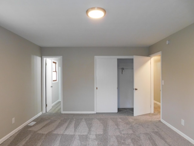 unfurnished bedroom with light colored carpet and a closet