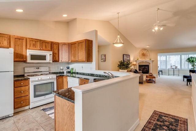 kitchen with open floor plan, a glass covered fireplace, white appliances, a peninsula, and brown cabinetry