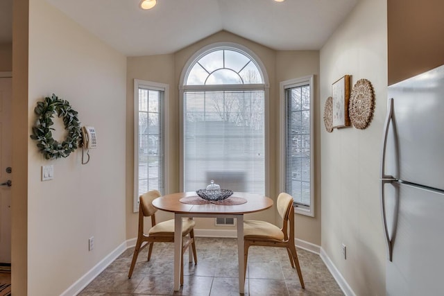 dining area with tile patterned floors, baseboards, and vaulted ceiling