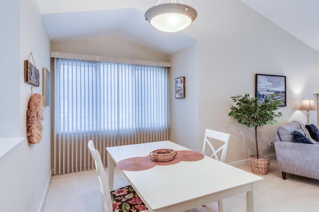 dining space featuring light carpet, baseboards, and lofted ceiling