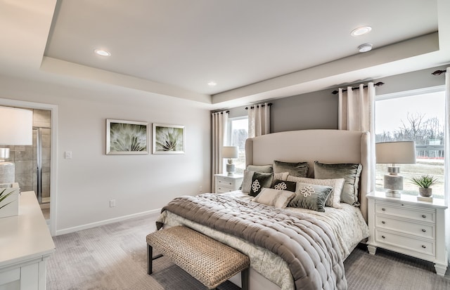 bedroom featuring carpet flooring, a tray ceiling, and ensuite bath