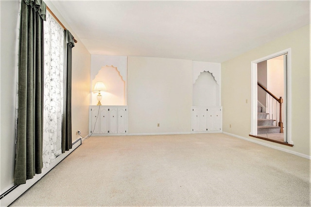 unfurnished room with baseboard heating and light carpet