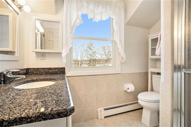 bathroom featuring tile patterned flooring, a baseboard heating unit, toilet, vanity, and tile walls