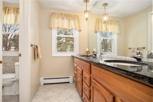 bathroom with toilet, vanity, a healthy amount of sunlight, and a baseboard heating unit