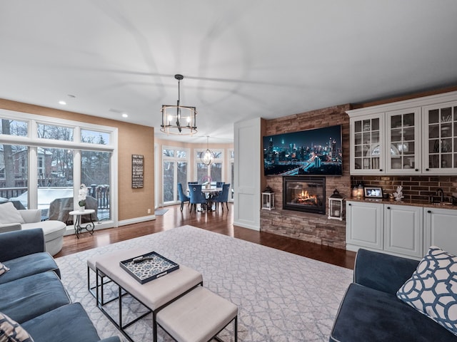 living room with sink, a fireplace, a chandelier, and hardwood / wood-style flooring