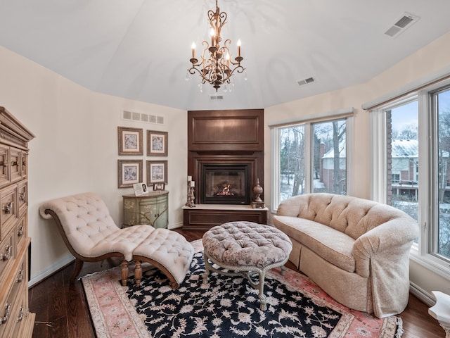 living area featuring a chandelier, a wealth of natural light, a fireplace, and dark wood-type flooring