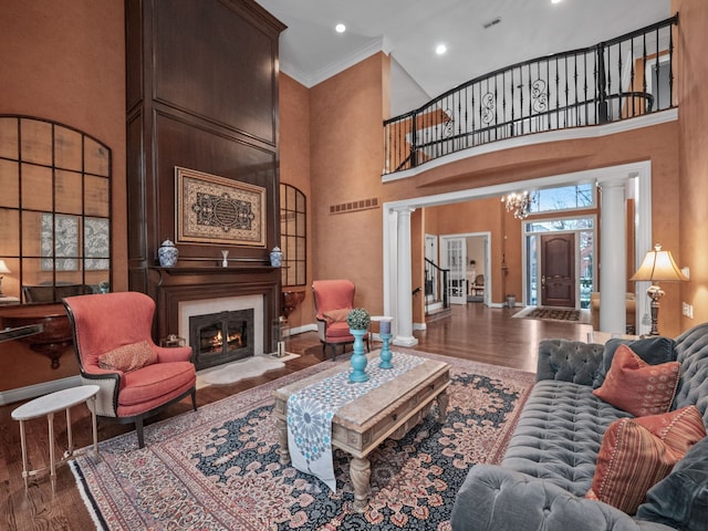 living room featuring decorative columns, a high ceiling, and hardwood / wood-style flooring