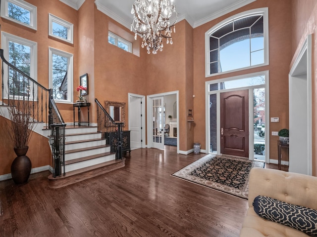 foyer featuring hardwood / wood-style flooring, a notable chandelier, ornamental molding, and a high ceiling