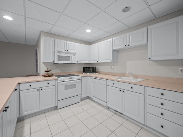 kitchen featuring a drop ceiling, white appliances, sink, light tile patterned floors, and white cabinetry