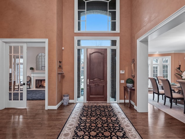 entrance foyer with dark hardwood / wood-style flooring, a towering ceiling, and crown molding