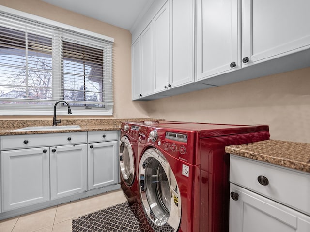 laundry room with washer and clothes dryer, cabinets, light tile patterned floors, and sink