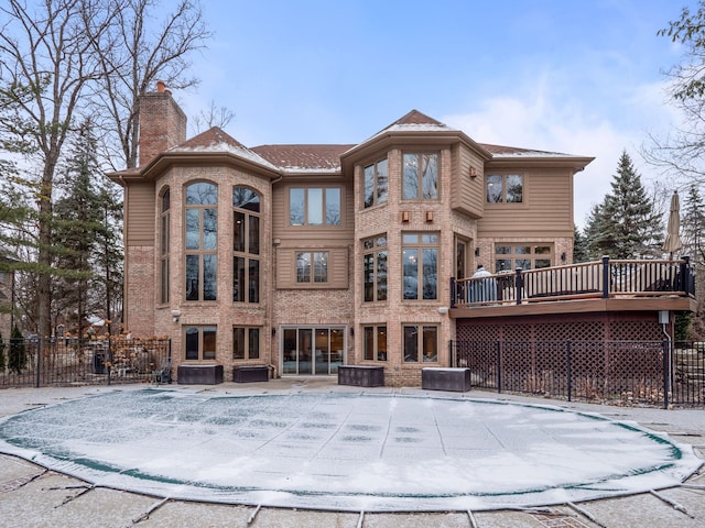 snow covered back of property featuring a wooden deck