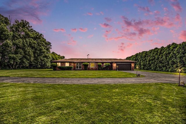 single story home with a garage and a lawn