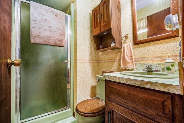 bathroom featuring vanity, toilet, and a shower with door