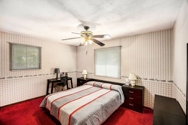 bedroom with ceiling fan, carpet flooring, and a textured ceiling