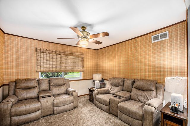 living room featuring ornamental molding, carpet, and ceiling fan