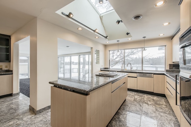 kitchen featuring a skylight, dishwasher, a kitchen island, and a healthy amount of sunlight