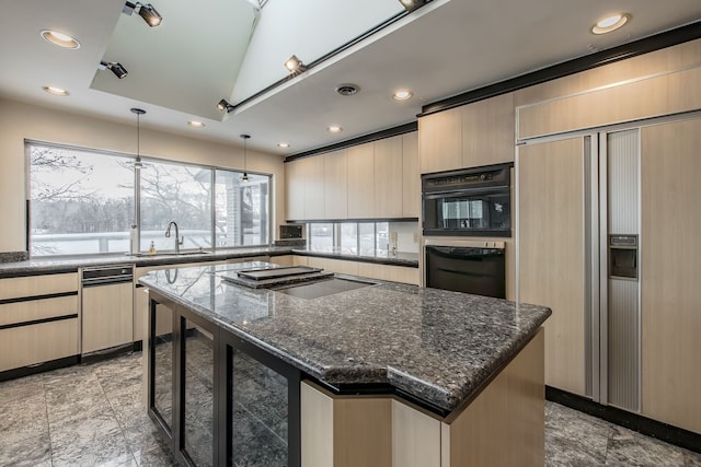 kitchen featuring paneled refrigerator, cooktop, sink, a kitchen island, and hanging light fixtures